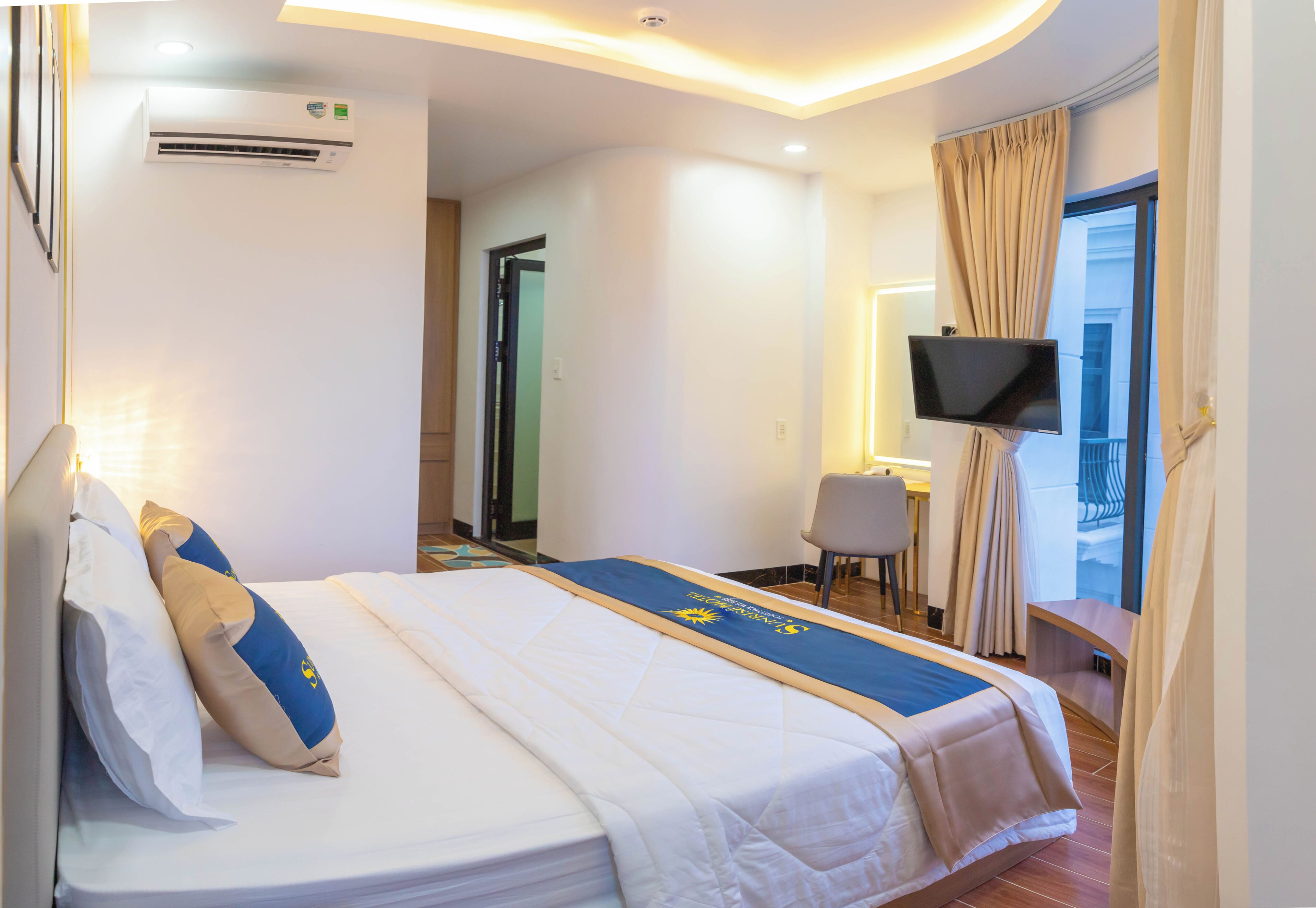 Une chambre d’hôtel avec un lit, une télévision, un bureau et un balcon avec des rideaux.