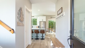 Una cucina moderna con mobili bianchi, un frigorifero in acciaio inossidabile e un'area bar con sgabelli.
