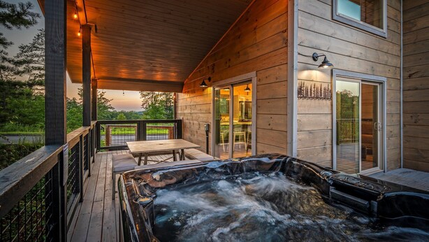 Une cabane en bois dotée d’un bain à remous, d’une terrasse et d’un coin repas.