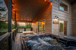Une cabane en bois dotée d’un bain à remous, d’une terrasse et d’un coin repas.