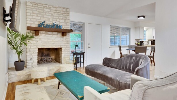 A living room with a fireplace, a sofa, a bench, and a dining area in the background. - Pool & Gameroom, pet friendly, 10 Minutes from South congress, 20 from Downtown (Austin)