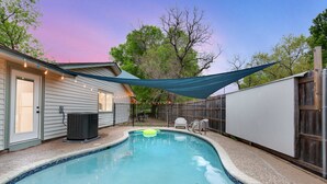 A backyard with a swimming pool, a covered patio, and a wooden fence. - Pool & Gameroom, pet friendly, 10 Minutes from South congress, 20 from Downtown (Austin)