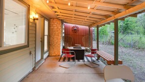 A covered patio with a table and chairs, a stone wall, and a wooden ceiling. - Pool & Gameroom, pet friendly, 10 Minutes from South congress, 20 from Downtown (Austin)