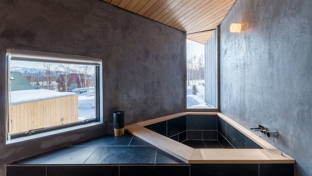 A modern bathroom with a large window, a wooden ceiling, and a black bathtub. - Niseko Village ski Chalet 4BDR Car Delica Included (niseko)