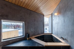 Une salle de bain moderne avec une grande fenêtre, un plafond en bois et une baignoire noire.