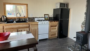 A kitchen with a stove, sink, microwave, and black refrigerator. - Located close to Tanalian River, amazing views and cozy setting. (Port Alsworth)