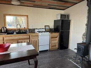 A kitchen with a stove, sink, microwave, and black refrigerator. - Located close to Tanalian River, amazing views and cozy setting. (Port Alsworth)