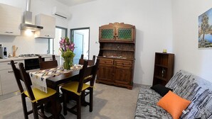 A modern kitchen with a dining area, a wooden cabinet, and a sofa with patterned bedding.