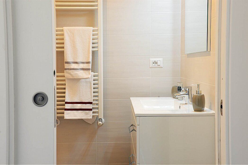 A bathroom with a towel rack, a sink, and a mirror.