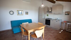 Une cuisine de taille réduite avec un coin repas, un canapé bleu et un sol carrelé.
