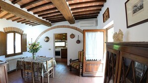 A dining area with a table and chairs, a vase with flowers, and a view into the kitchen. - Casa Fattorina F: A characteristic and welcoming two-story independent house surrounded by the greenery, with Free WI-FI. (Chiusi)