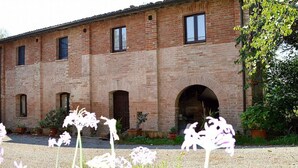 A brick building with multiple windows and arched doorways, surrounded by gravel and potted plants. - Casa Fattorina F: A characteristic and welcoming two-story independent house surrounded by the greenery, with Free WI-FI. (Chiusi)