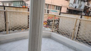 A balcony with a metal railing, a marble floor, and a view of a building with a sign that reads "Admission Open First Feet May School". - Comfort Inn Hotel.Near MayurVihar Metro1 (New Delhi)