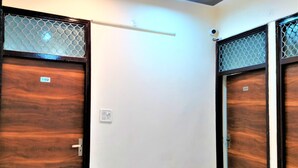 A hallway with two wooden doors, each marked with a number. The floor is tiled, and there is a ceiling light fixture. - Comfort Inn Hotel.Near MayurVihar Metro1 (New Delhi)