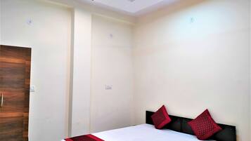 A bedroom with a bed, two red pillows, a ceiling fan, and a wooden door.