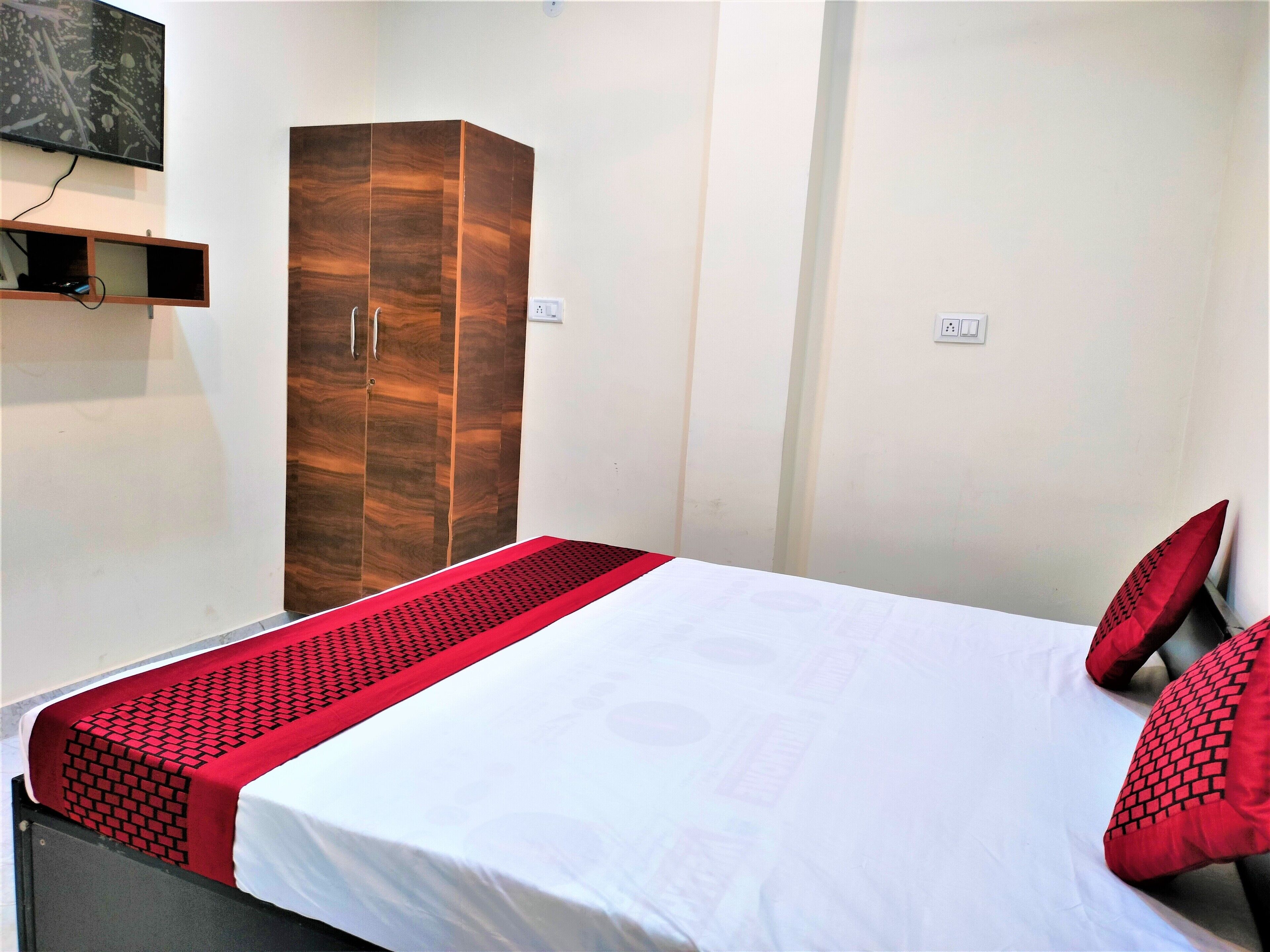 A hotel room with a bed, a wardrobe, and a television mounted on the wall.