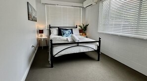 Cozy retreat with a central bed, ceiling fan, and air conditioning unit.