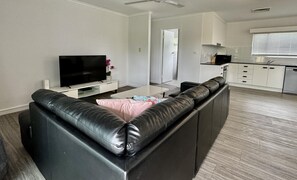 Relax in this stylish living room with a comfortable sofa, flat-screen TV, and a convenient kitchen area.