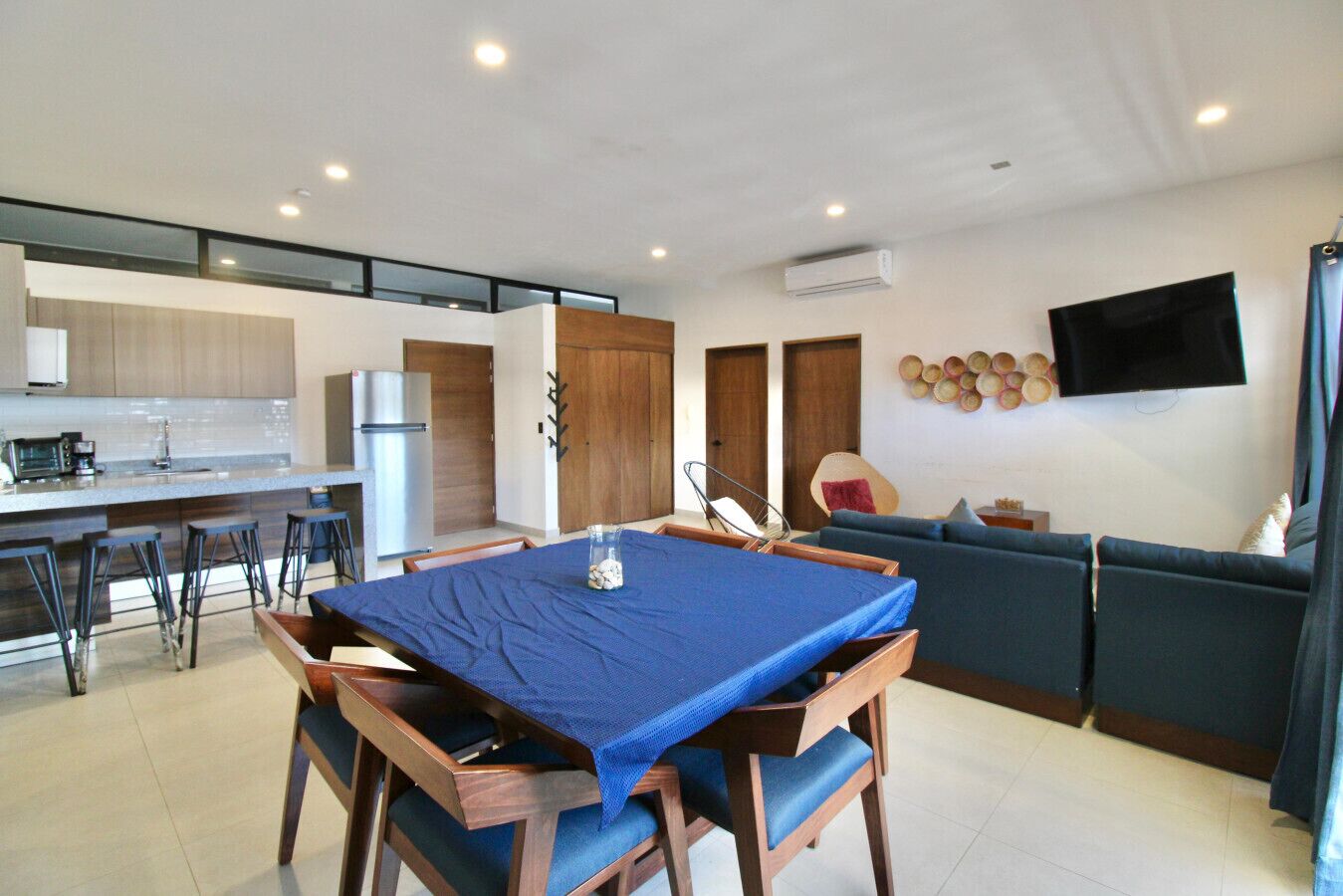 Una cocina moderna con comedor, una sala de estar con sofá y un televisor de pantalla plana en la pared.