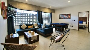 A modern living room with a sectional sofa, a dining table, and a pool table.