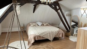 A cozy attic bedroom with a bed, a hanging chair, and a rustic wooden ceiling. - Charming country house with pool (Saint-Seurin-sur-l'Isle)