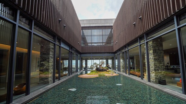 A modern building with a central courtyard featuring a water feature and stone elements. - Pine Beach Golf Hotel (Haenam)
