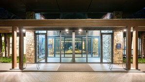 A hotel entrance with a glass door, stone pillars, and a covered walkway. - Pine Beach Golf Hotel (Haenam)