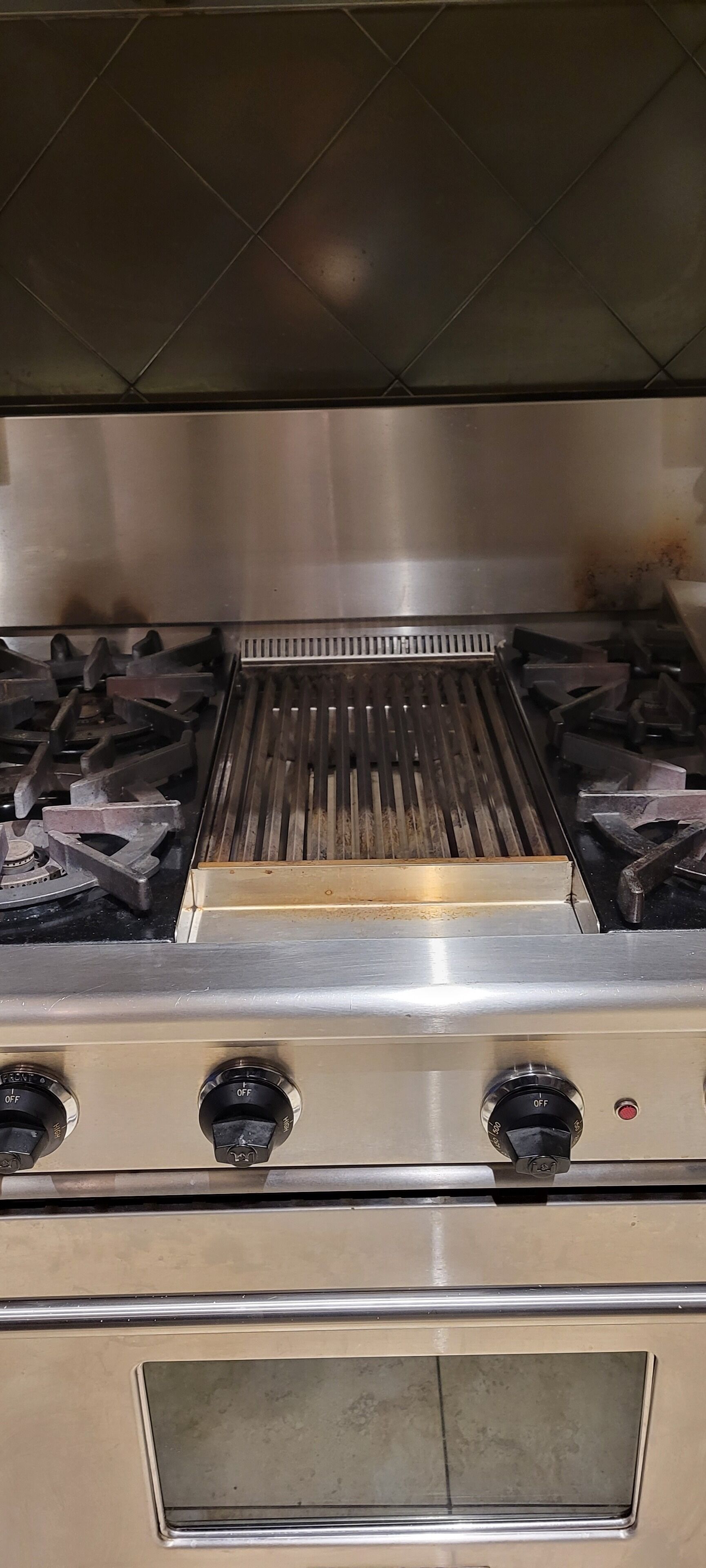 A kitchen with a stainless steel range hood, a gas stove with four burners, and a stainless steel oven.