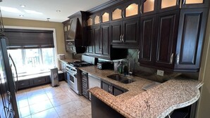 A modern kitchen with dark cabinetry, granite countertops, and stainless steel appliances. - Villa Delrose Waterfront (Montréal)