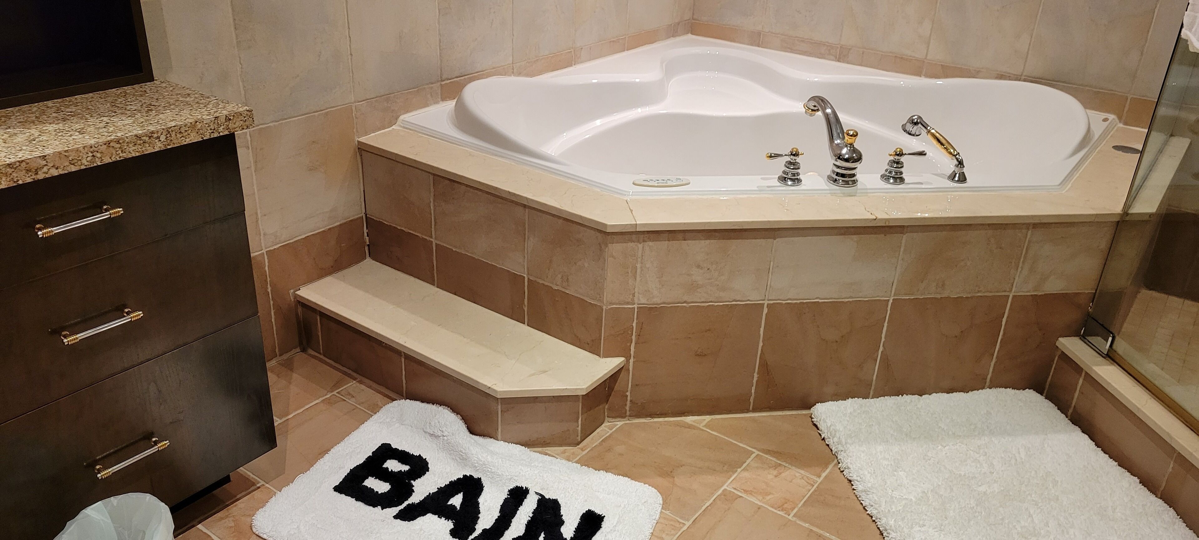 Une salle de bain avec une baignoire, un meuble-lavabo avec des tiroirs et un petit marchepied menant à la baignoire.