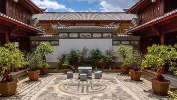 A courtyard with traditional architecture, potted plants, and a patterned floor.