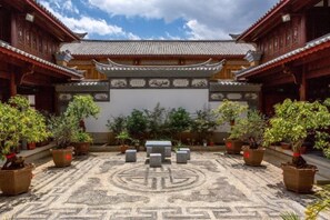 A courtyard with traditional architecture, potted plants, and a patterned floor. - Jianyang Inn (Jianchuan)