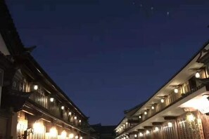 A traditional building with multiple floors and balconies, likely a hotel or guesthouse, with lights on. - Jianyang Inn (Jianchuan)