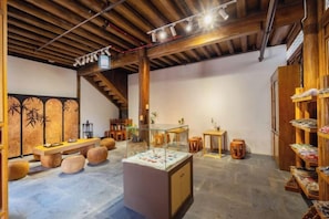 A spacious room with a wooden ceiling, a central display area, and a staircase.