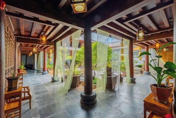Un interior tradicional con vigas de madera, una columna central y plantas en macetas.