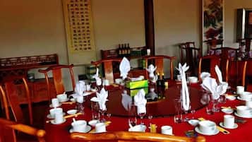A traditional dining table set with white tableware and napkins, surrounded by wooden chairs.