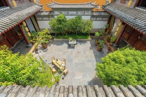 A courtyard with traditional architecture, potted plants, and a seating area.