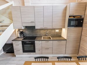 Una cocina compacta con horno integrado, un lavamanos y una cafetera.