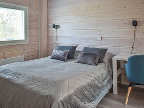 A bedroom with a bed, a bedside table, a chair, and a window. - Villa galdu b by Interhome (Kittilä)