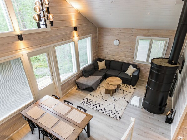 A modern interior with a sofa set, a dining table with placemats, and a large black heater.