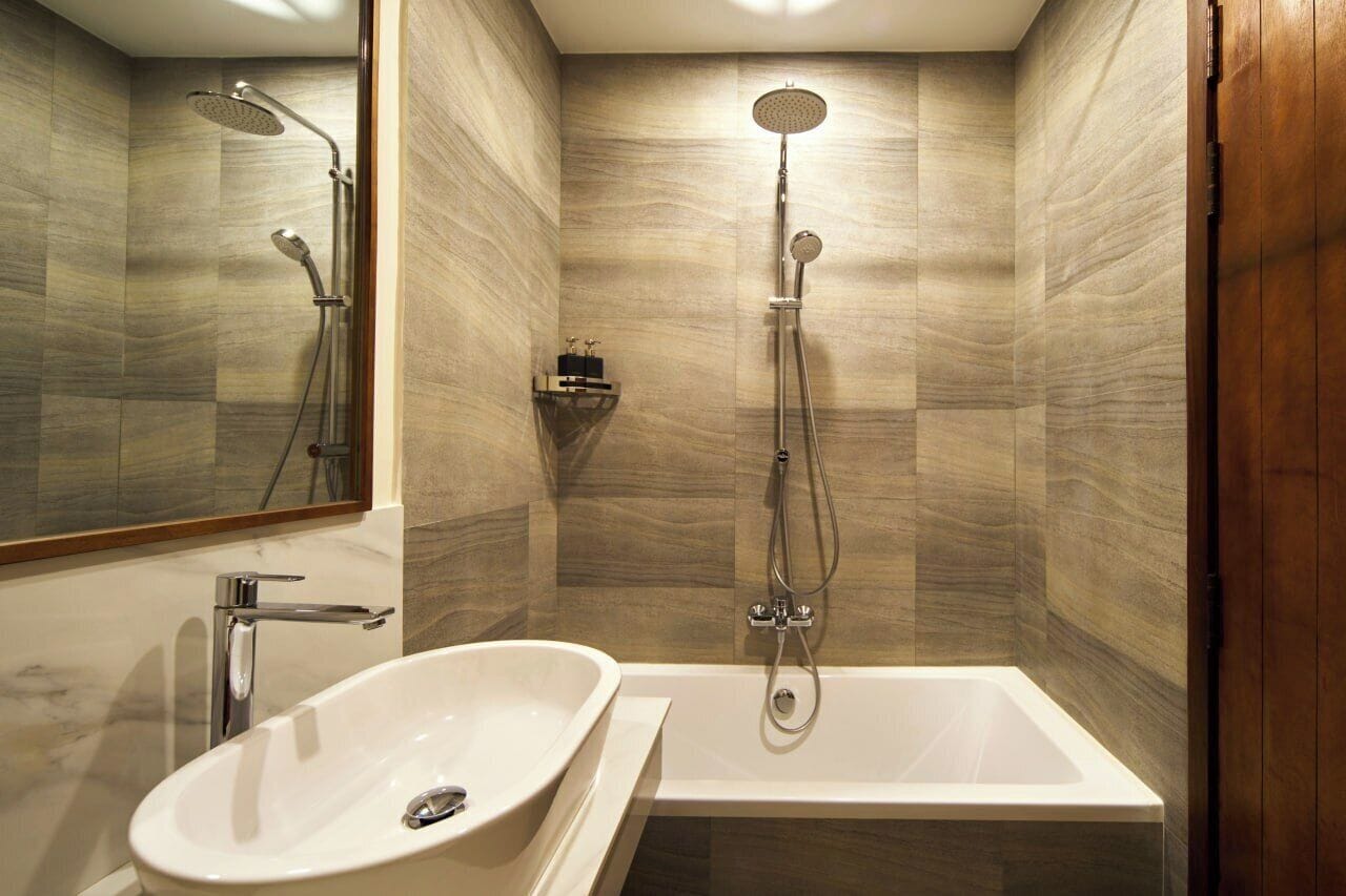 Un baño moderno con una bañera independiente, un cabezal de ducha empotrado y un espejo grande.