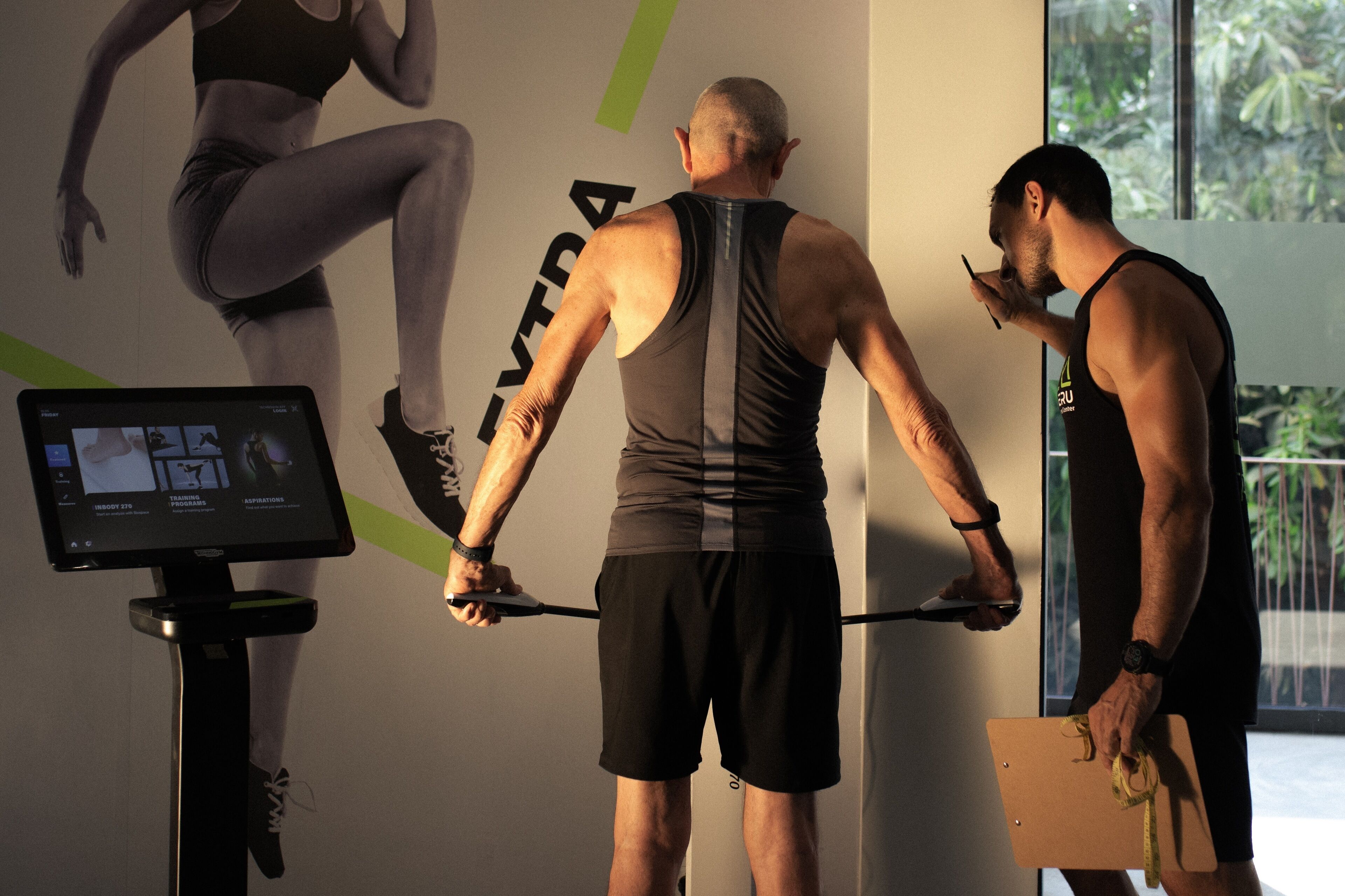 A gym with exercise equipment, a digital display, and a large poster of a woman exercising.