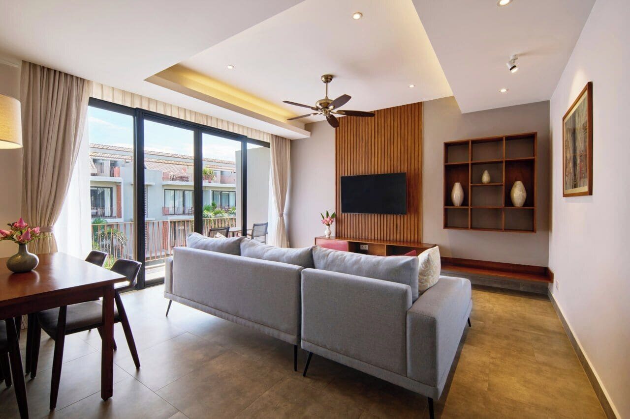 Ein modernes Wohnzimmer mit Sofa, Fernseher und Balkonblick.