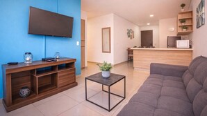 A modern living room with a flat-screen TV, wooden entertainment unit, and a grey sofa.