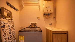 A compact bathroom with a Bosch water heater, a wooden cabinet, and a towel rack with decorative text.