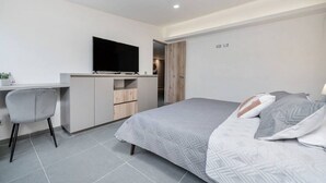 A modern bedroom with a bed, a desk, and a television.