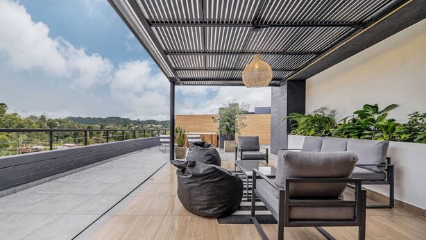 A rooftop terrace with a modern outdoor seating area, including a table and chairs, and a hanging light fixture. - Olive 404 · Penthouse 2 hab Dúplex-Jacuzzi privado en terraza (Alto Palmas)