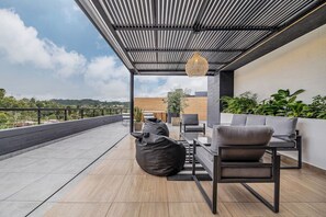 Eine Dachterrasse mit einem modernen Sitzbereich im Freien, inklusive Tisch und Stühlen sowie einer hängenden Leuchte.