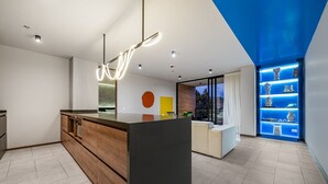 A modern kitchen with a central island, built-in appliances, and a blue accent wall. - Olive 404 · Penthouse 2 hab Dúplex-Jacuzzi privado en terraza (Alto Palmas)