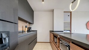 A modern kitchen with dark cabinetry, a wooden countertop, and a built-in oven. - Olive 404 · Penthouse 2 hab Dúplex-Jacuzzi privado en terraza (Alto Palmas)